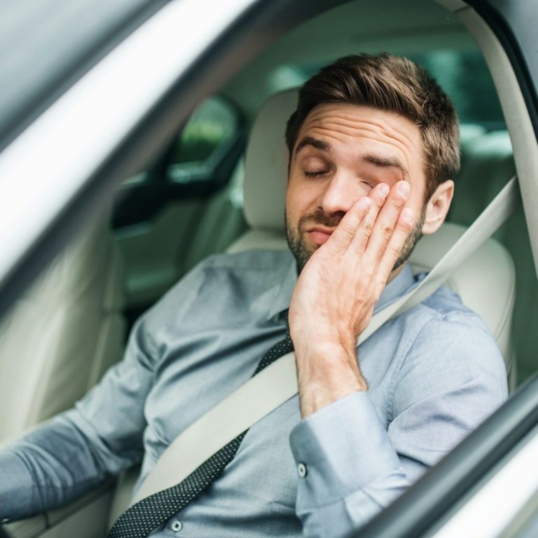 Müder Mann im Auto mit Anzug – Symbol für Erschöpfung und Symptome von Testosteronmangel vor der Therapie mit TestoCare