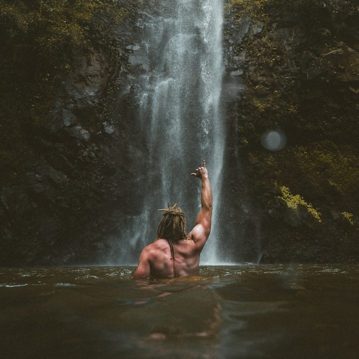 Mann mit definierten Rückenmuskeln steht unter Wasserfall – Symbol für Kraft und Vitalität durch Testosterontherapie bei TestoCare